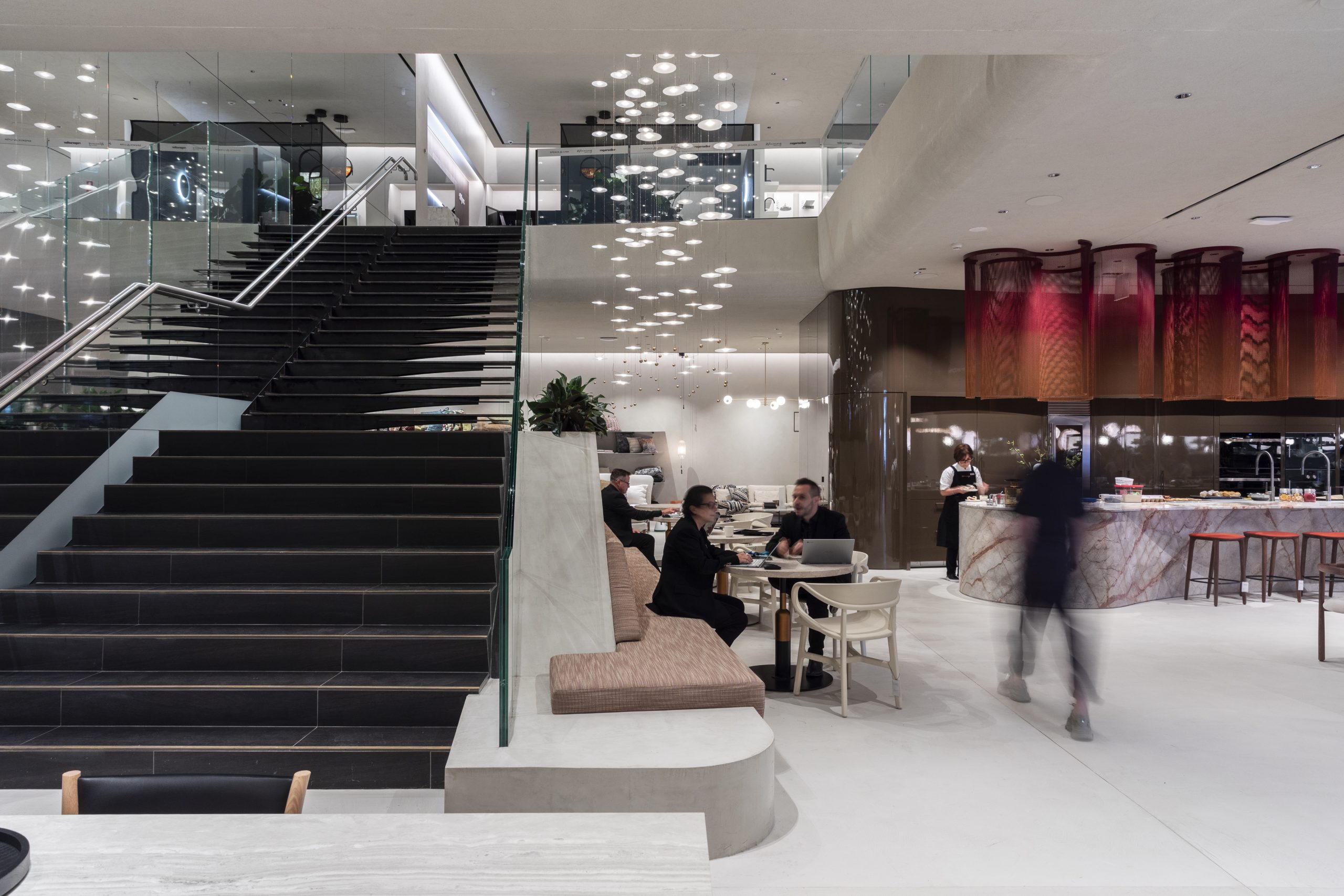 Seating area within a departmetnstore, next to a staircase and underneath a custom O-O-O installation by VANTOT