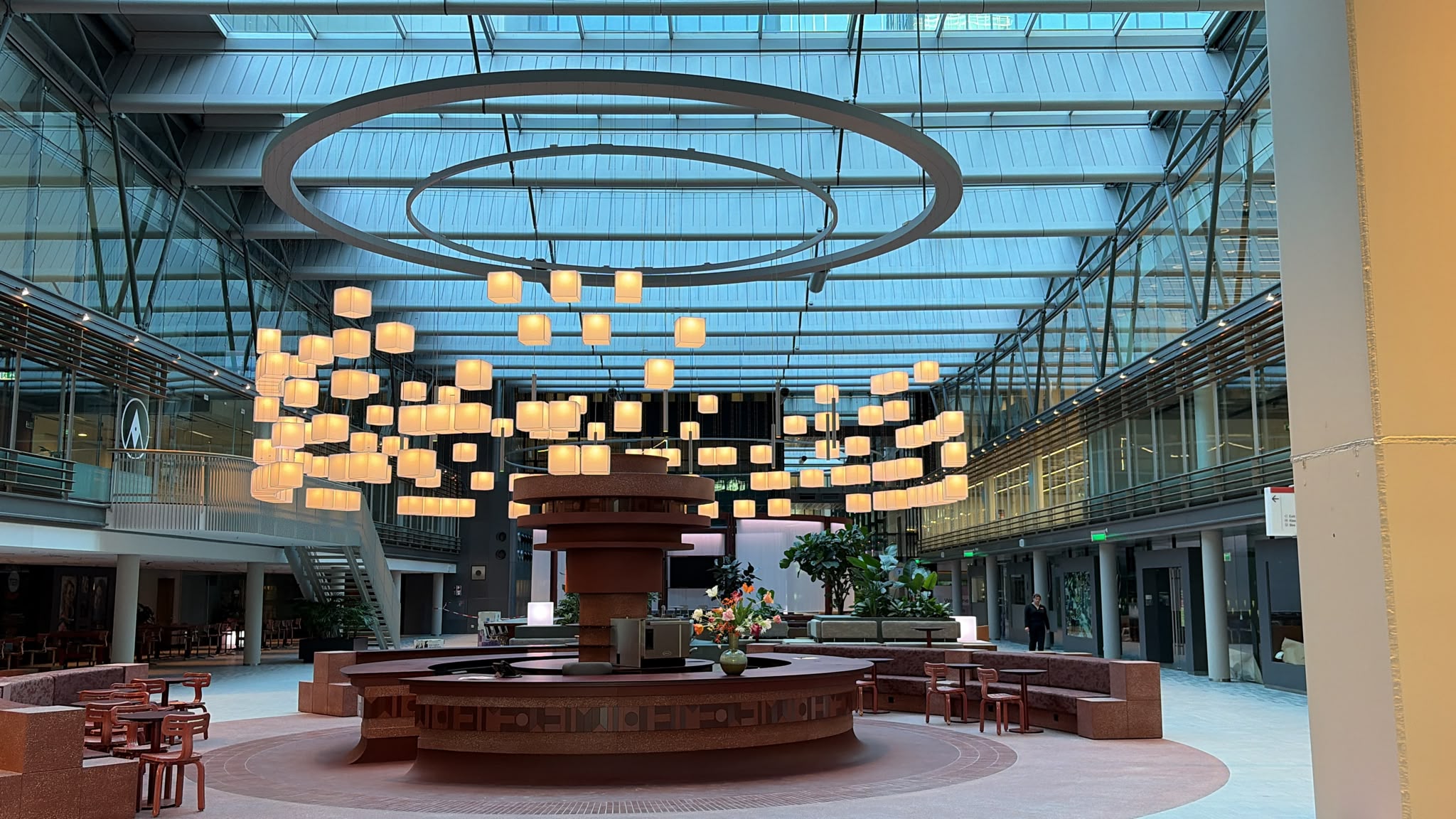 WTC living lobby KUBIUS bespoke chandelier by VANTOT glowing above the central bar in the Living Lobby of World Trade Center Amsterdam at dusk, designed in collaboration with TANK for CBRE.